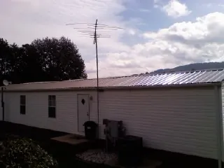New metal roof on a single wide mobile home with a TV antenna in Hudson