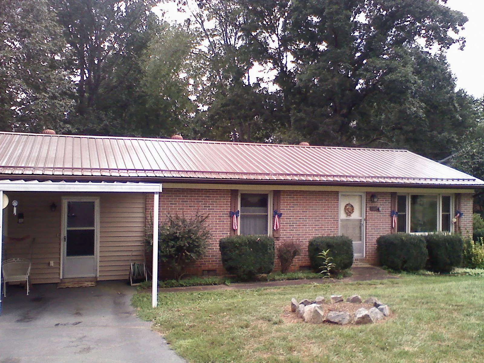 Bronze metal roof and carport on a brick ranch home — Roof Repair work by our crew in Hudson